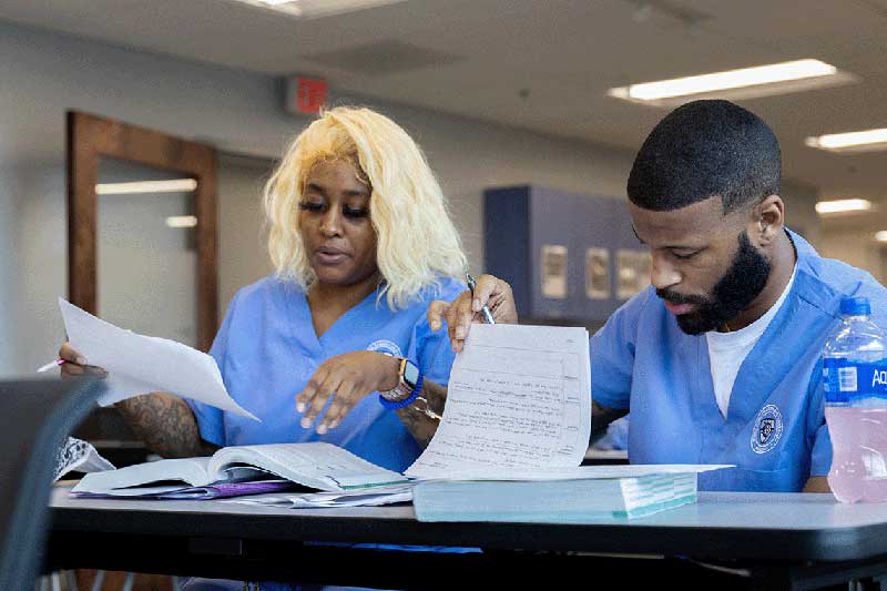 2 nursing students in classroom working on classwork