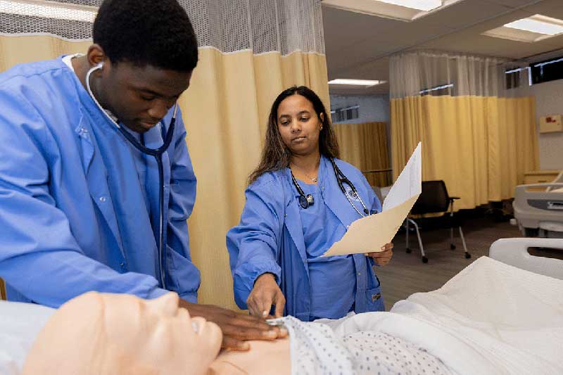 2 NDMU students working on a manikin