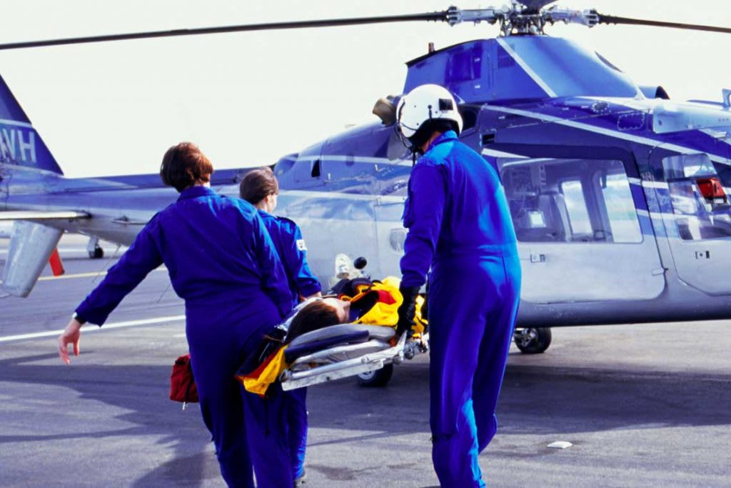 emergency personnel helping someone onto a helicopter