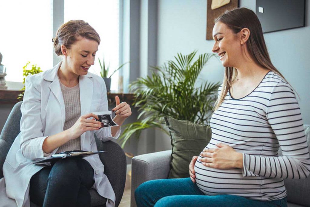 nurse looking at sonogram with expecting mom