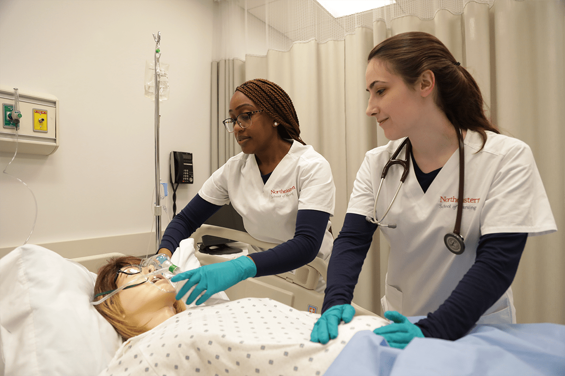 two Northeastern nursing students working in sim lab