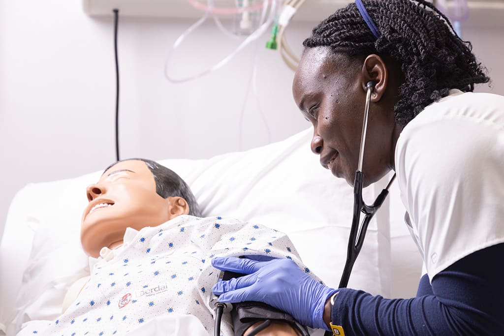 Northeastern nursing student using stethoscope on manikin