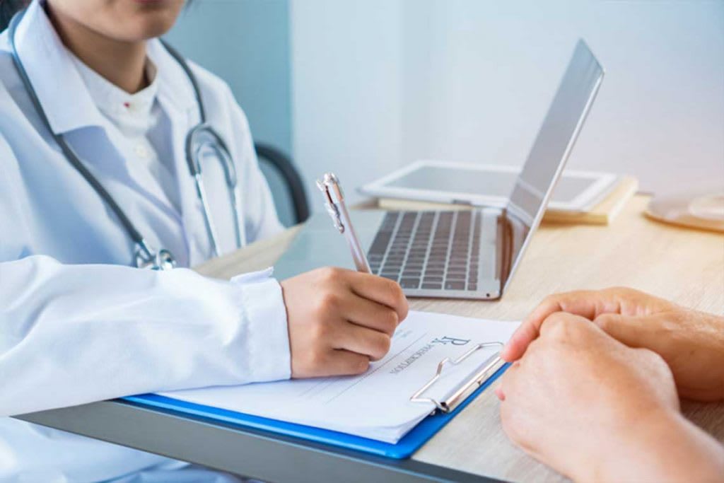 closeup of nurse hands writing on clipboard at desk