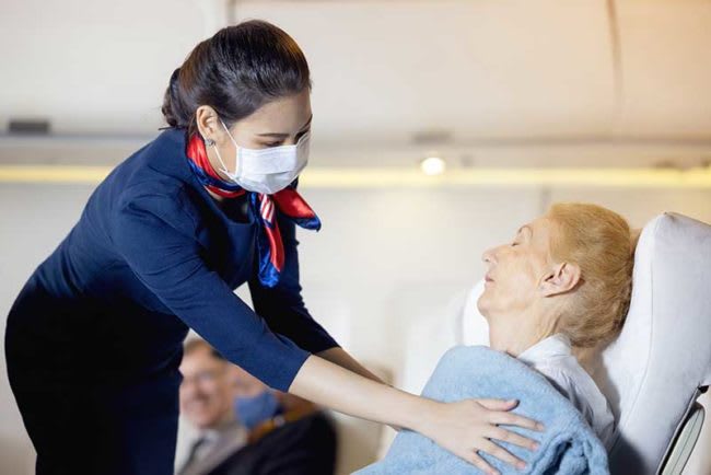 nurse helping give patient blanket on airplane