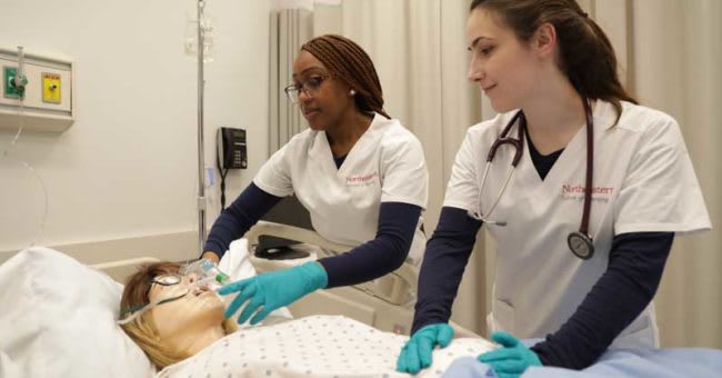 Two Northeastern ABSN students with a maternity simulation manikin