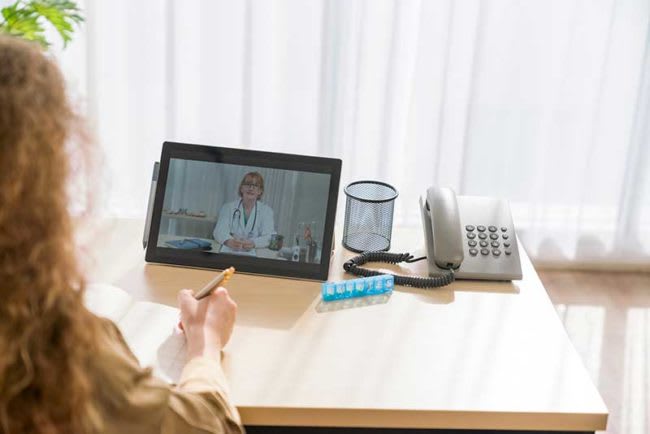 woman sitting at home talking to nurse online