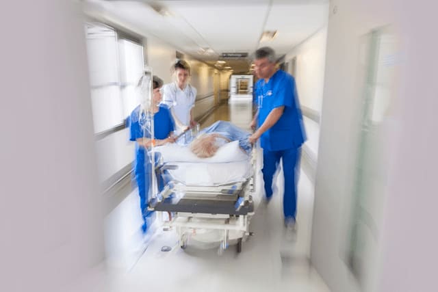 nurses rushing patient on bed through hospital hallway