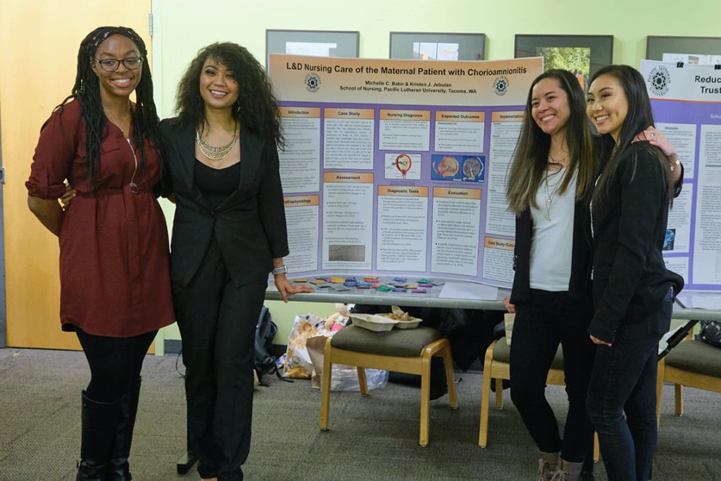 students posing in front of Nursing Capstone project presentations