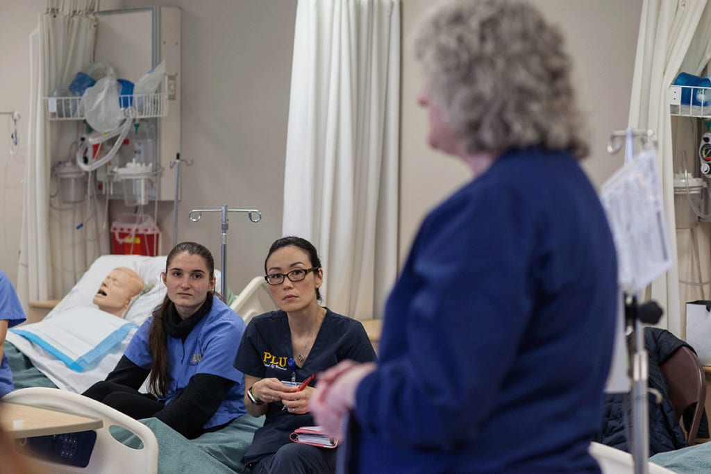 nursing instructor speaking to students in lab