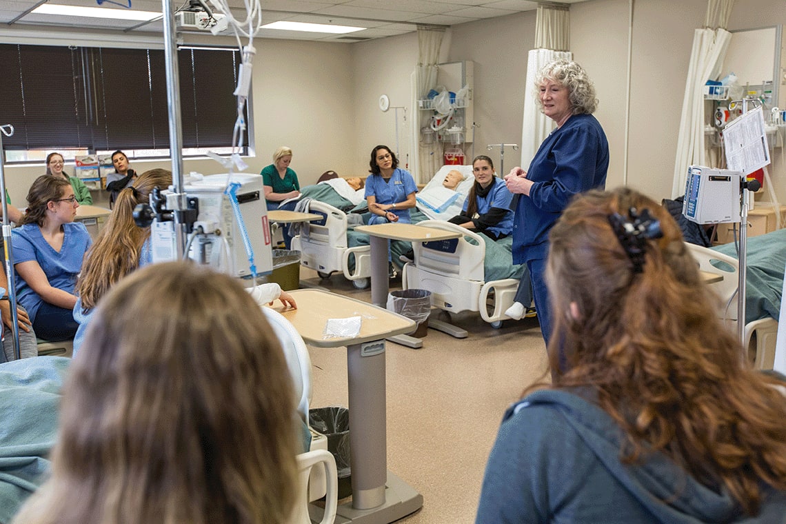 ABSN instructor speaking to nursing students in lab