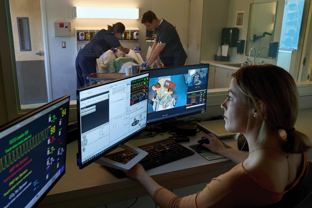 PLU nursing students working in sim lab and looking at computer monitors