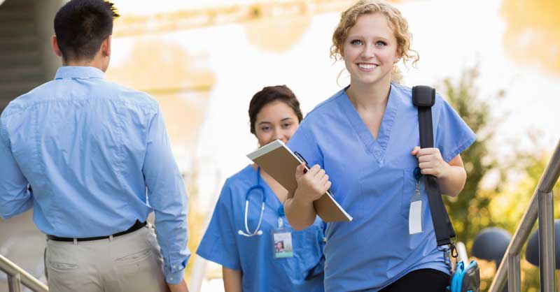 smiling nurse with backpack walking up stairs