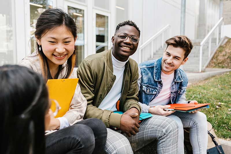 students sitting outside together smiling