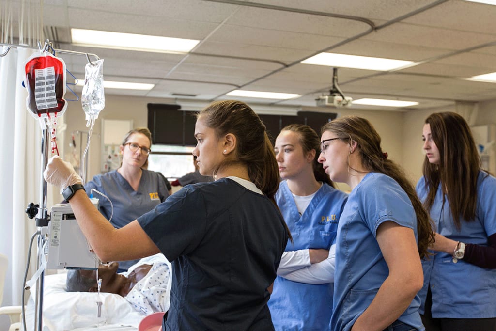 PLU ABSN students looking at IV in simulation lab