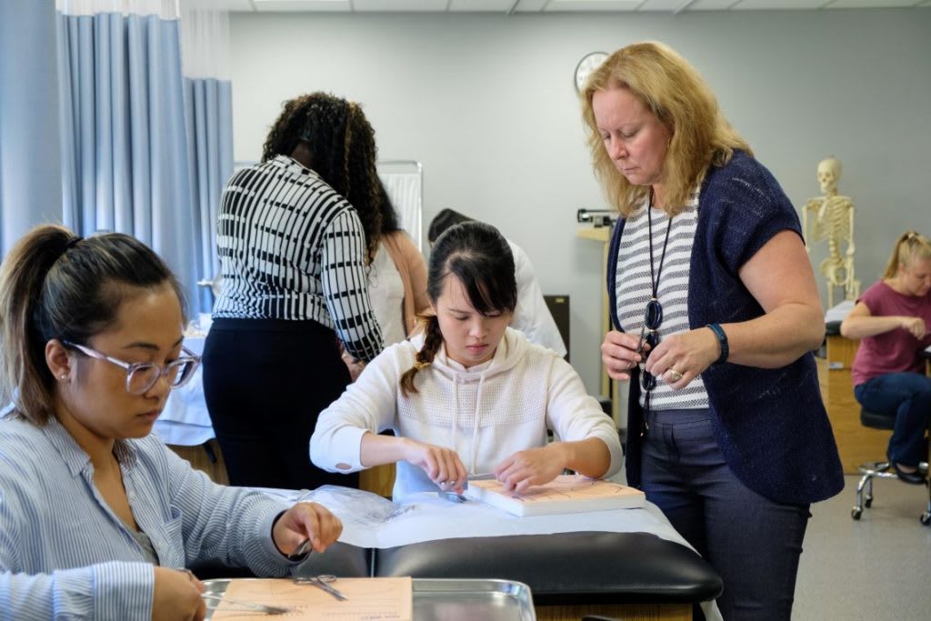 nursing students with instructor practicing sutures