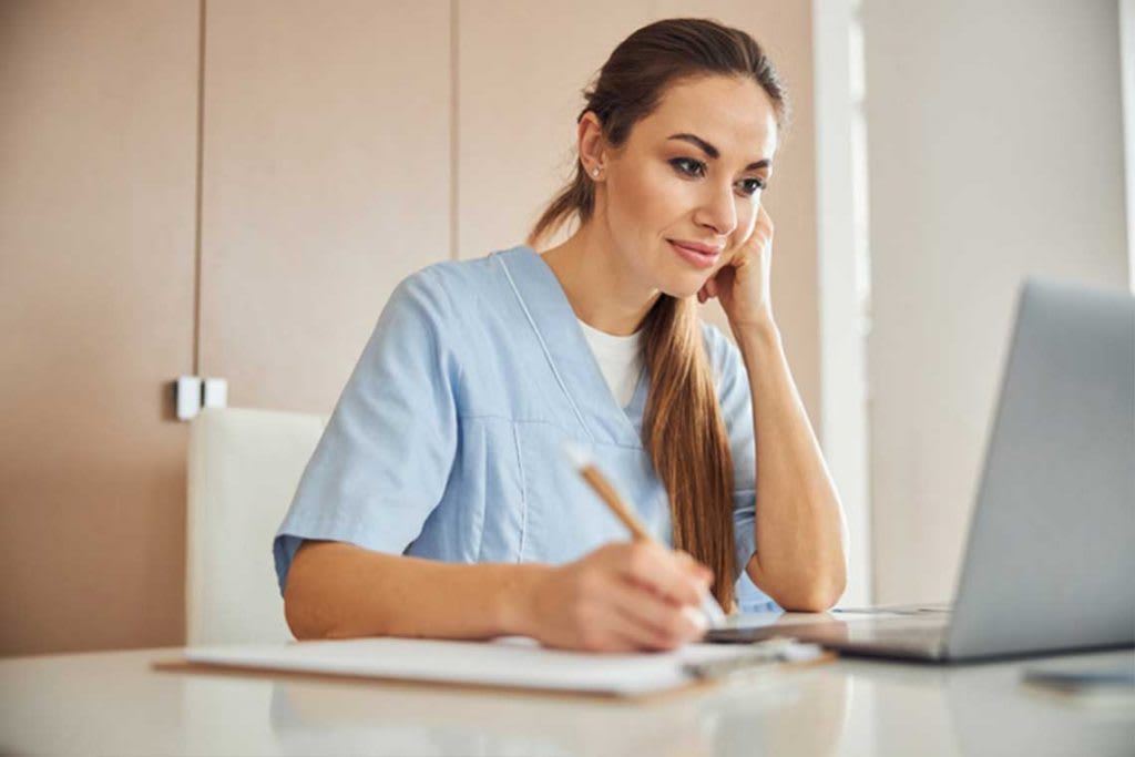 nurse sitting at desk looking at laptop