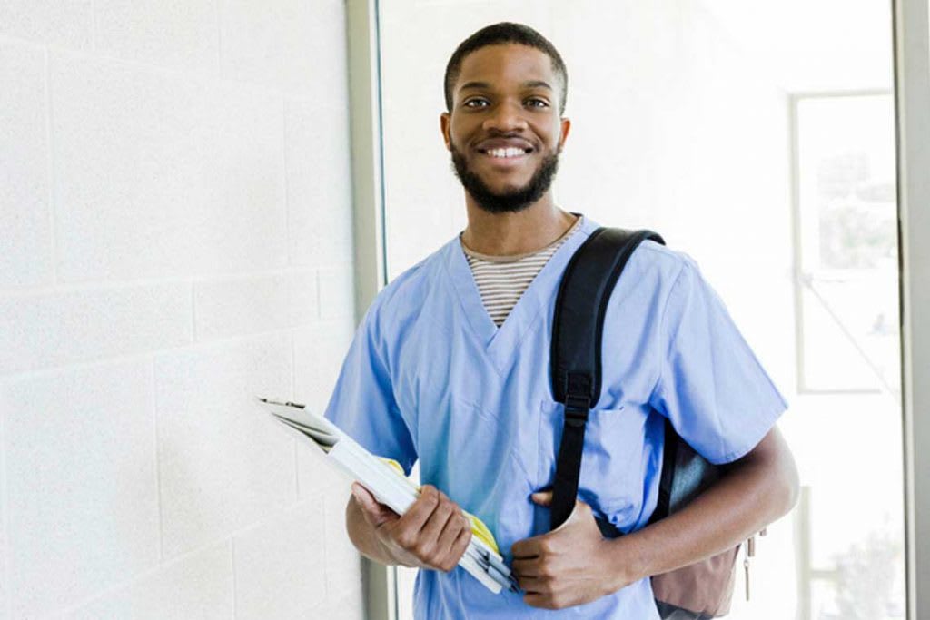 nurse with backpack and books smiling at camera