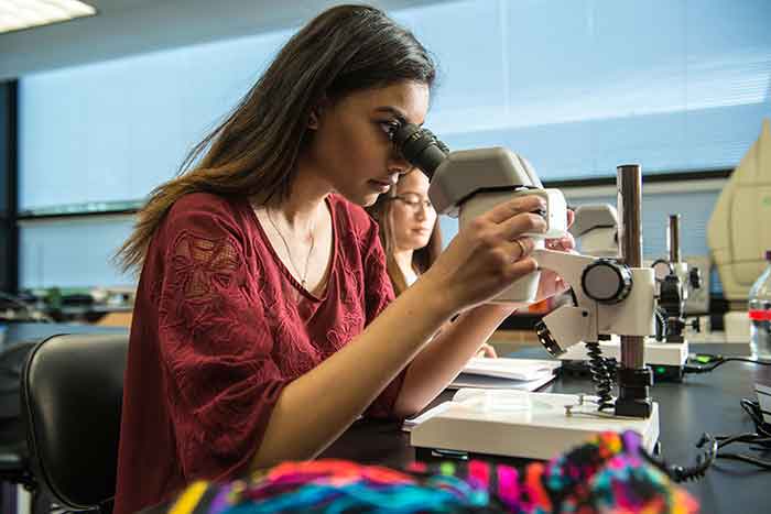 student in science lab using microscope