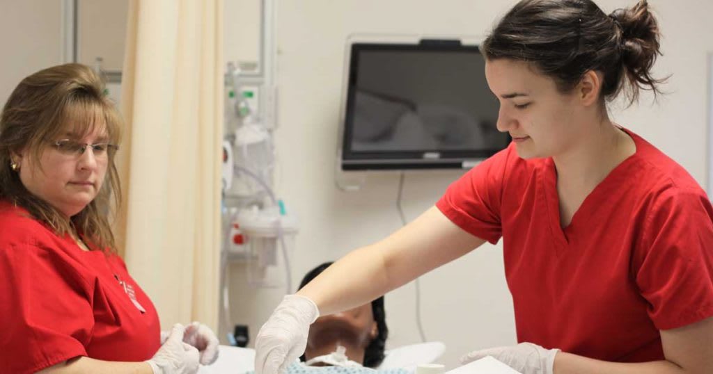 two nursing students working on sim manikin