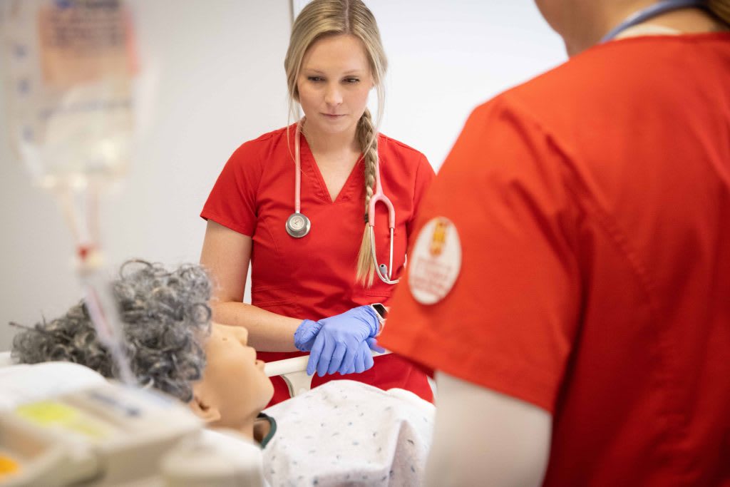 nursing students working with a simulation manikin