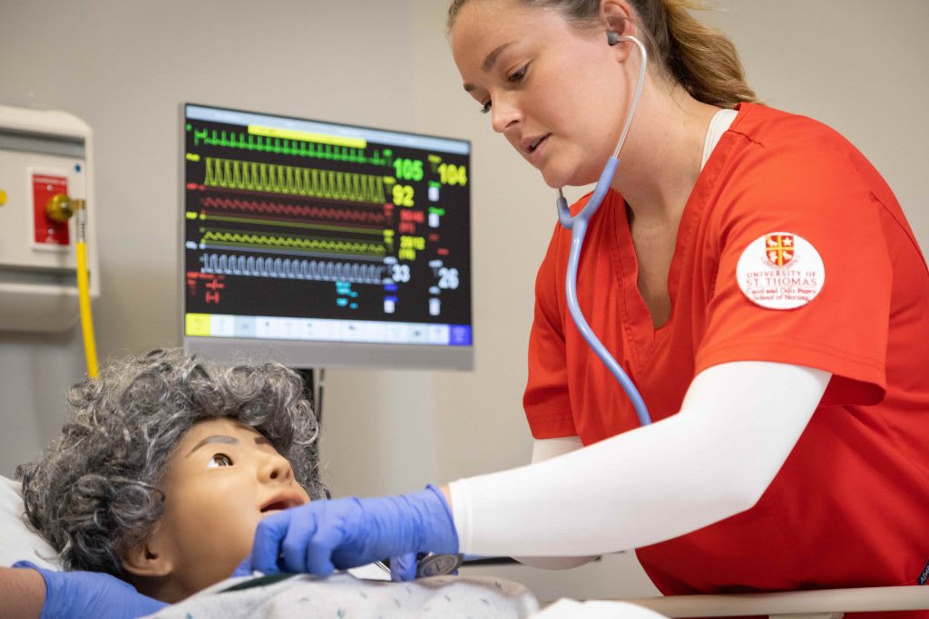 UST ABSN student in lab working with sim manikin