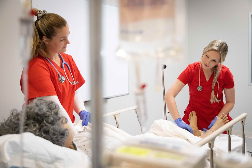 two UST nursing students working in sim lab