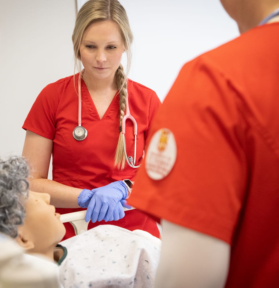 two nurses looking over manikin