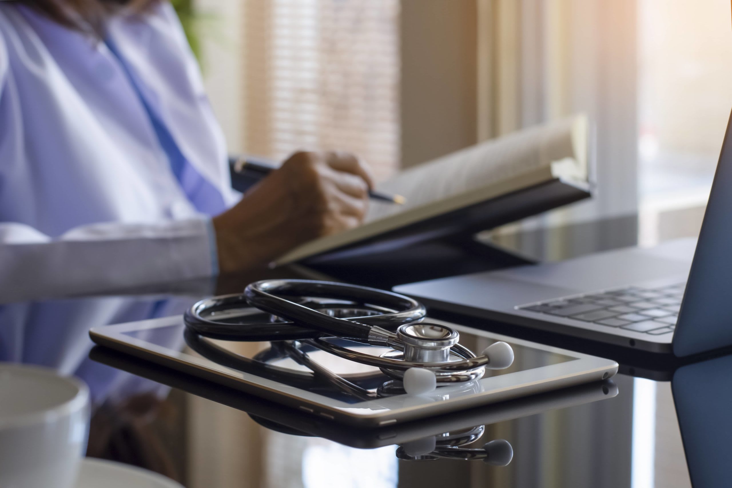 nursing student with textbook sitting at computer