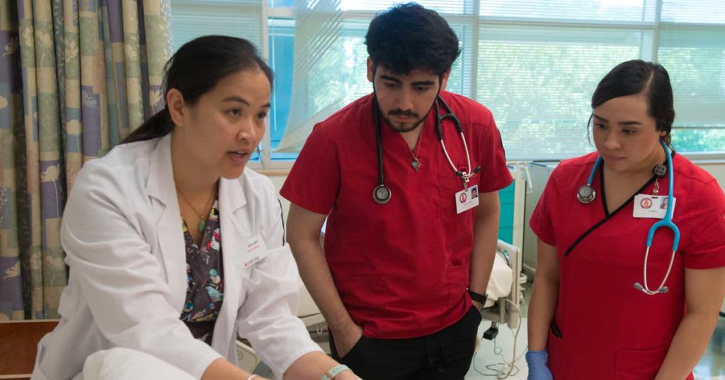 nursing instructor working in lab with two nursing students