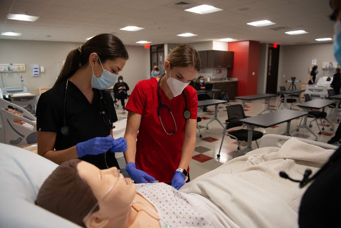 2 UIW ABSN students working together on a practice manikin