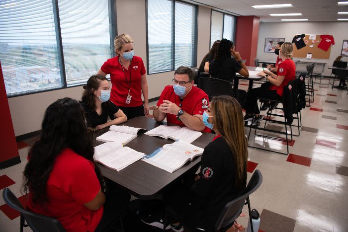 Nursing students sitting around a table studying with textbooks