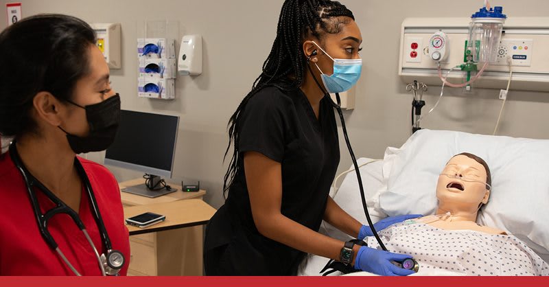 2 nursing students working in a lab setting on a manikin