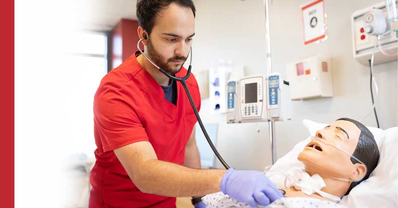 UIW ABSN student using stethoscope on sim manikin