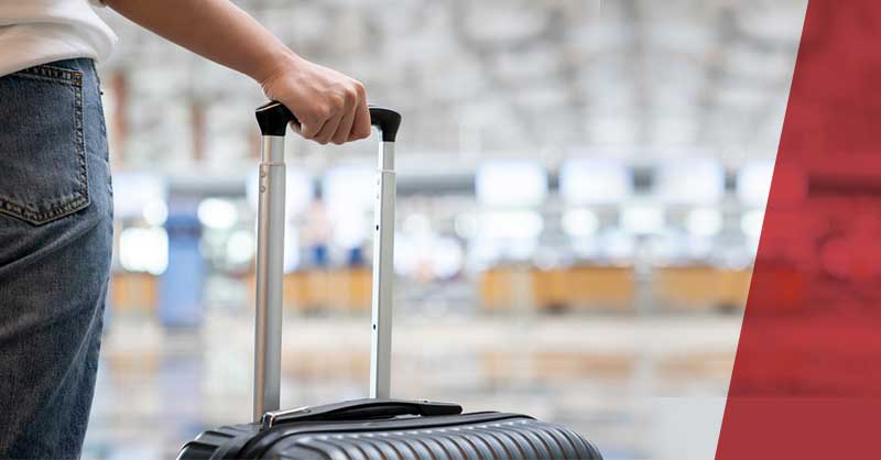 person's hand holding handle of travel luggage