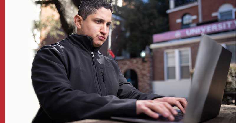 student sitting at desk using laptop