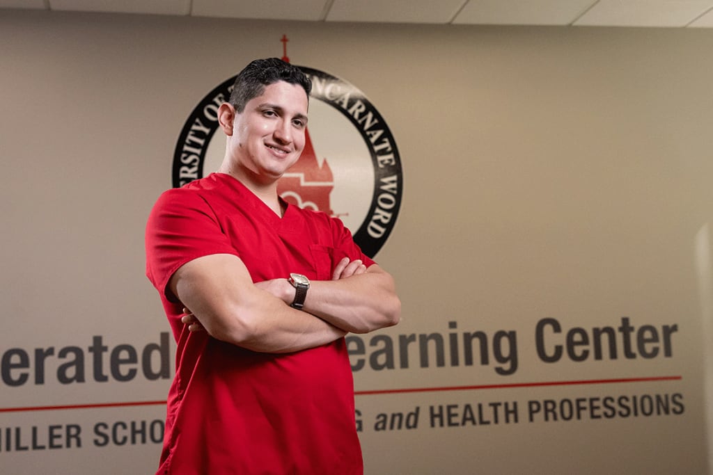 UIW nursing student in red scrubs smiling with arms crossed