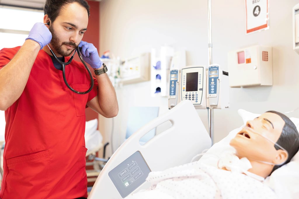 UIW nursing student wearing stethoscope with a manikin