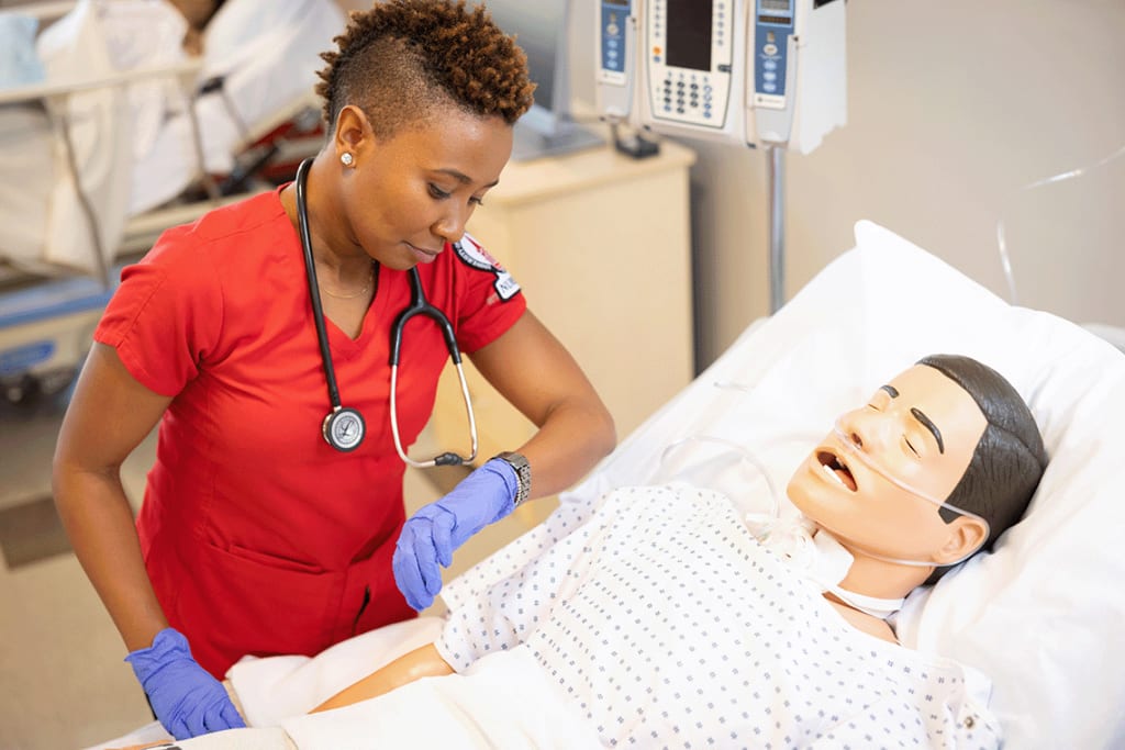 nursing student in lab setting with manikin