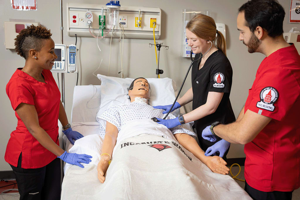 3 UIW nursing students in a lab setting working on a manikin