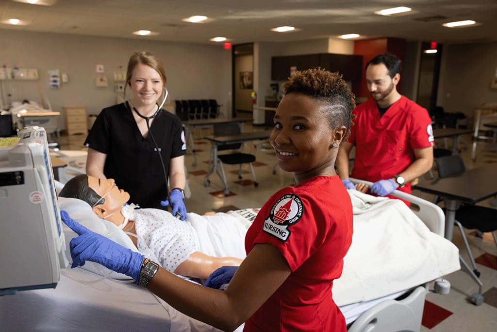 3 UIW students working in a lab setting on a manikin