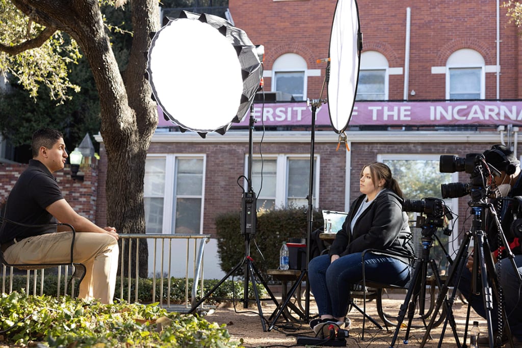 Nursing student sitting in front of cameras and lights being interviewed