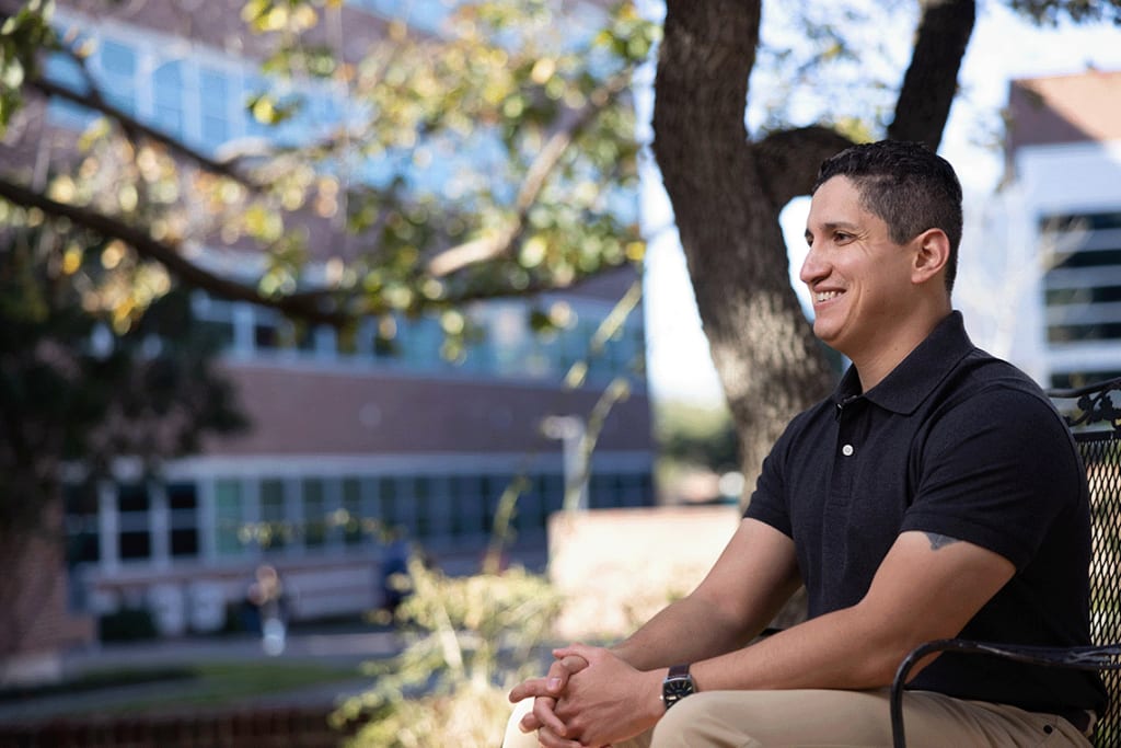 Nursing student sitting outside on a bench smiling