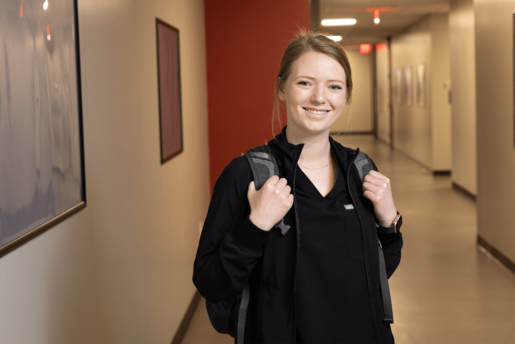 UIW nursing student in hallway wearing backpack and smiling