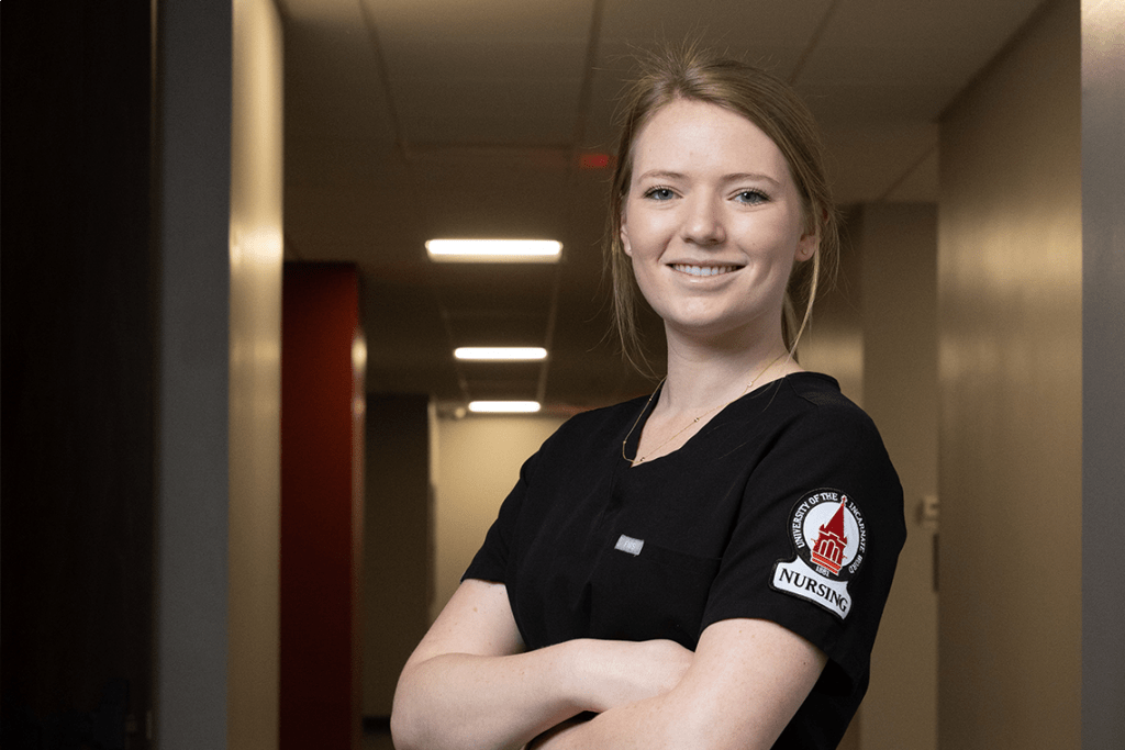 UIW nursing student in scrubs smiling with arms crossed