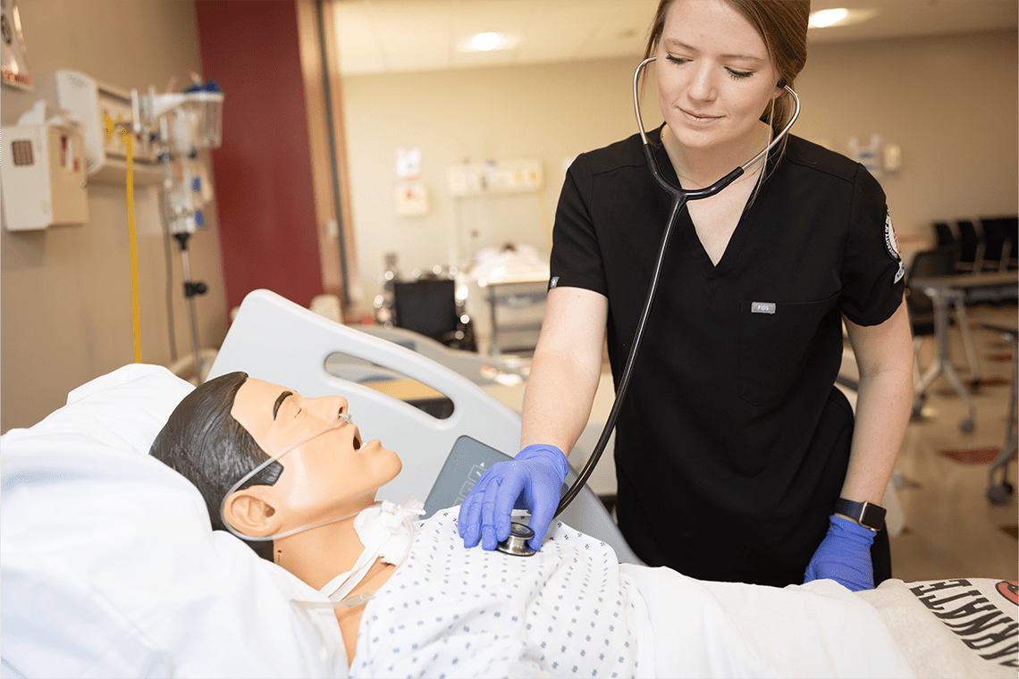 UIW nursing student in black scrubs working on a lab manikin