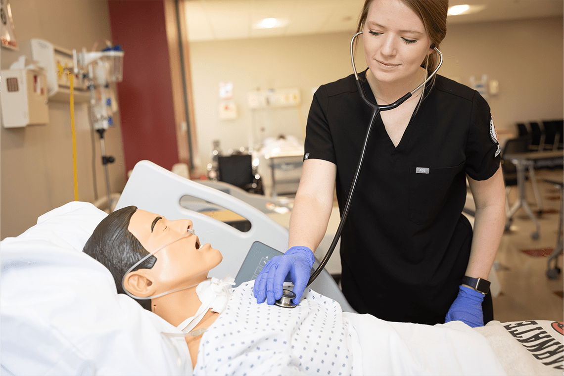 UIW nursing student in black scrubs working on a lab manikin 