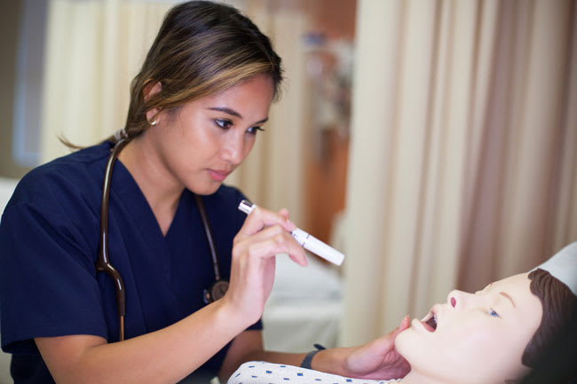 Utica ABSN student examining simulation manikin