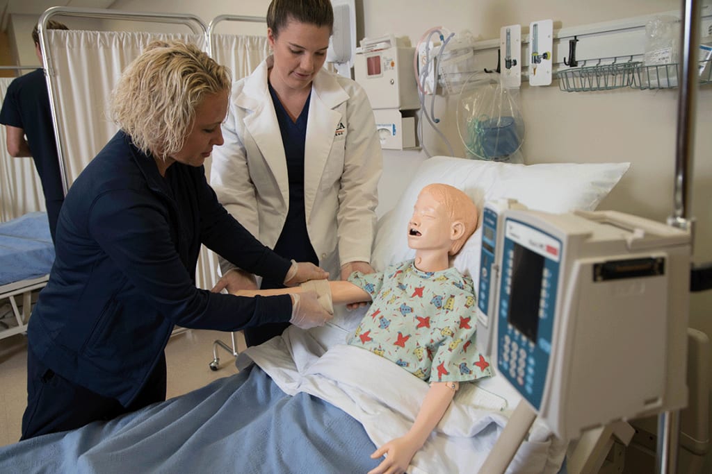 Utica students working on a child nursing manikin