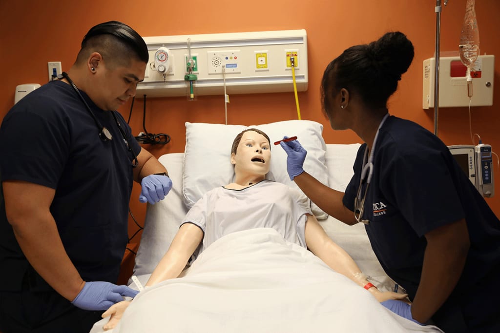 2 Utica students working on a manikin