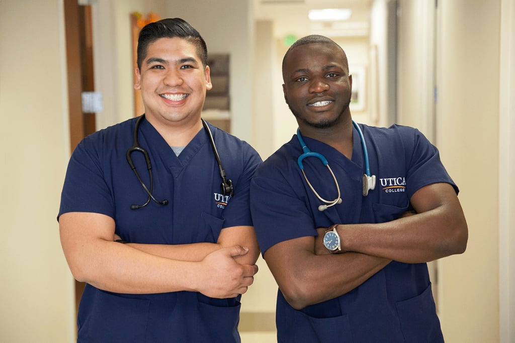 2 Utica nursing students smiling with their arms crossed